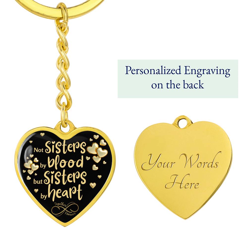 Gold-toned heart-shaped keychain with a black background and printed message: 'Not Sisters by blood, but Sisters by heart.' Small gold hearts surround the message. with th option to engraved a message in the back of the pendant