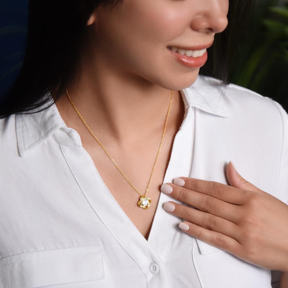 A smiling woman wearing a love knot necklace