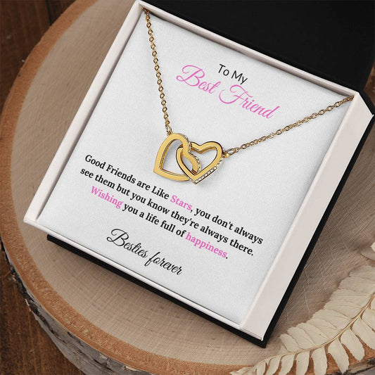 A necklace in a gift box with a message to a best friend. on wood table . The necklace features two interlocking hearts, on a gold finish. The message on the box reads: "To My Best Friend, Good Friends are Like Stars, you don't always see them but you know they're always there. Wishing you a life full of happiness. Besties forever."